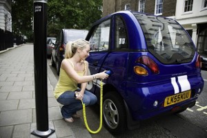Young woman charging electric car --- Image by © Nancy Honey/cultura/Corbis